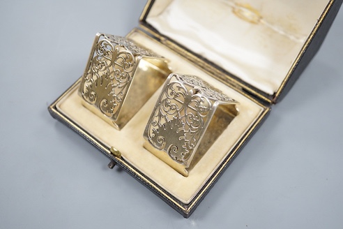 A late Victorian cased pair of pierced silver triangular napkin rings, by Goldsmiths & Silversmiths Co Ltd, London, 1900, with engraved inscription.